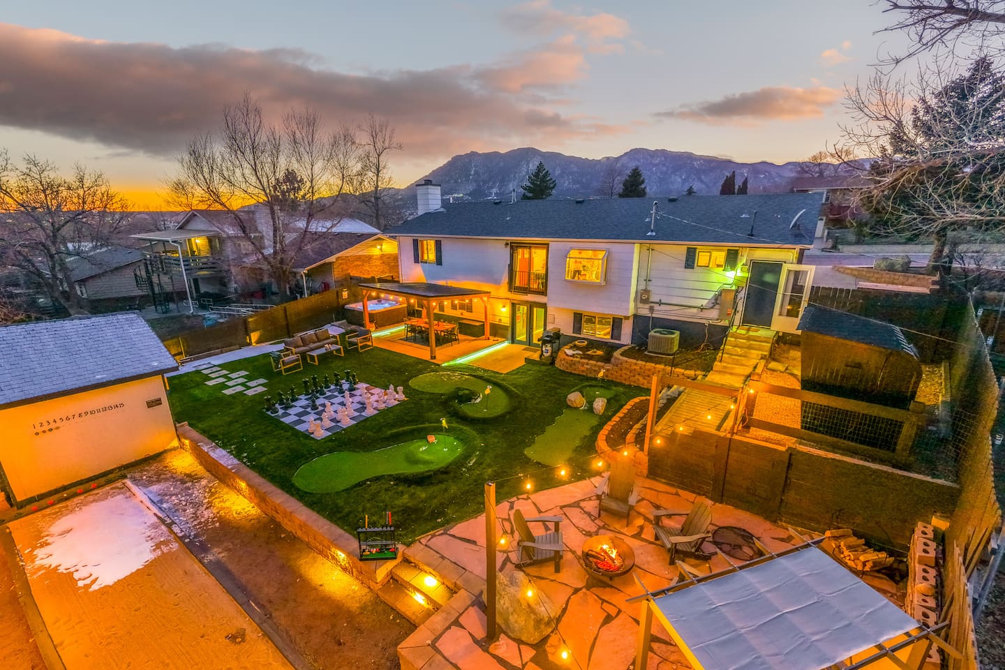 The backyard of a vacation rental featuring a mini-golf course, fire pit, and seating area.